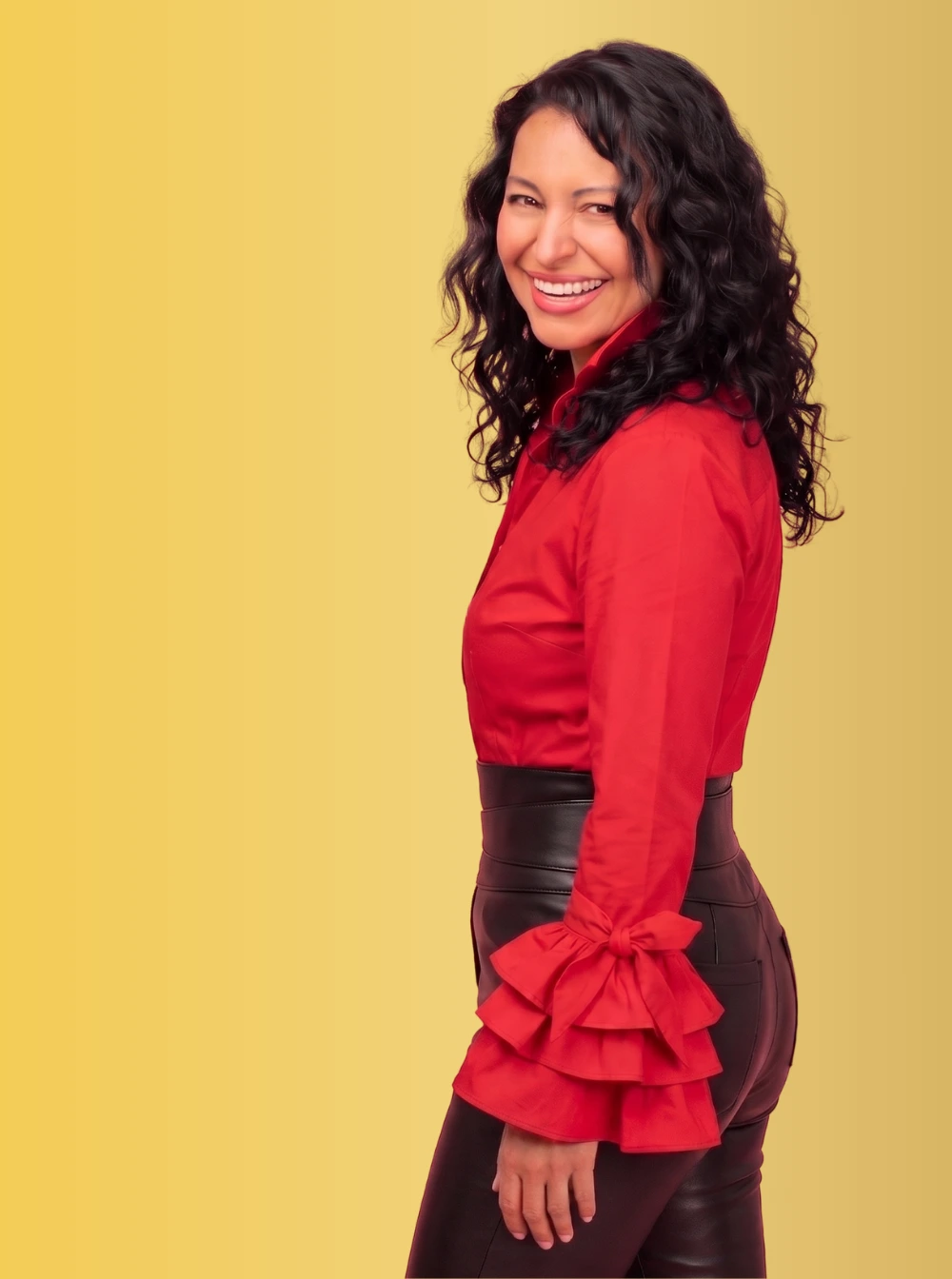 Stand-up comedian Mariza Brussolo standing wearing a red blouse smiling
