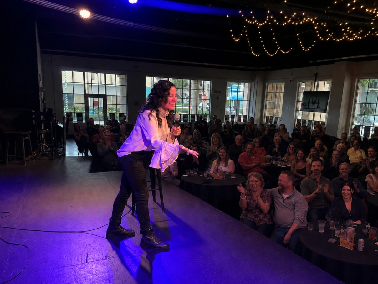 Comedian Mariza Brussolo performing on stage in front of a crowd