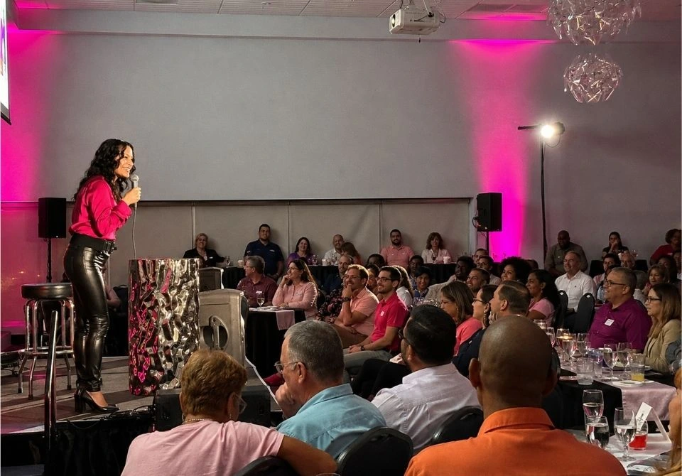 Comedian Mariza Brussolo performing for a live audience at a corporate event