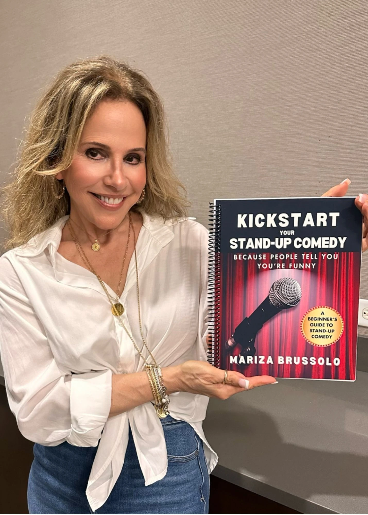 Woman holding a copy of Kickstart Your Stand-Up Comedy by Mariza Brussolo
