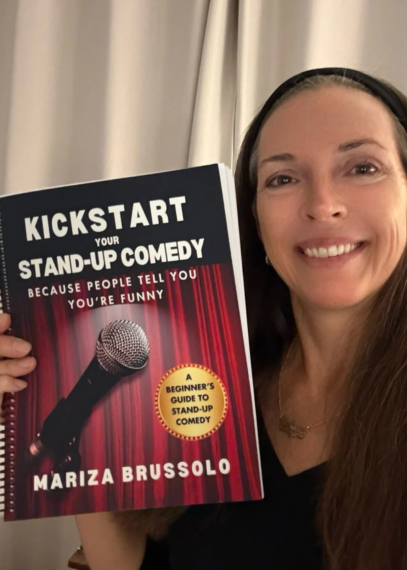 Reader holding a copy of Kickstart Your Stand-Up Comedy by Mariza Brussolo