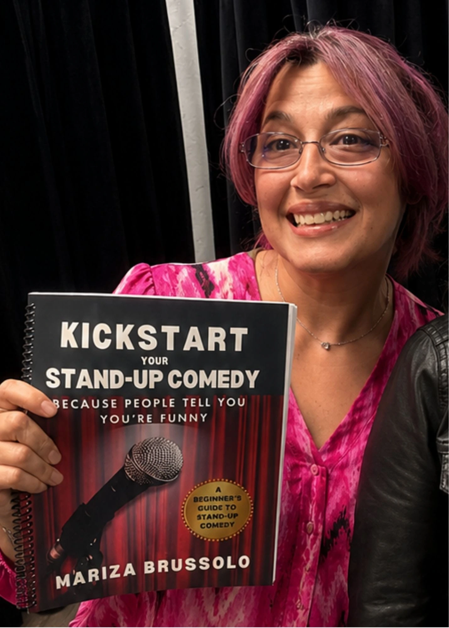 Woman holding a copy of Kickstart Your Stand-Up Comedy by Mariza Brussolo