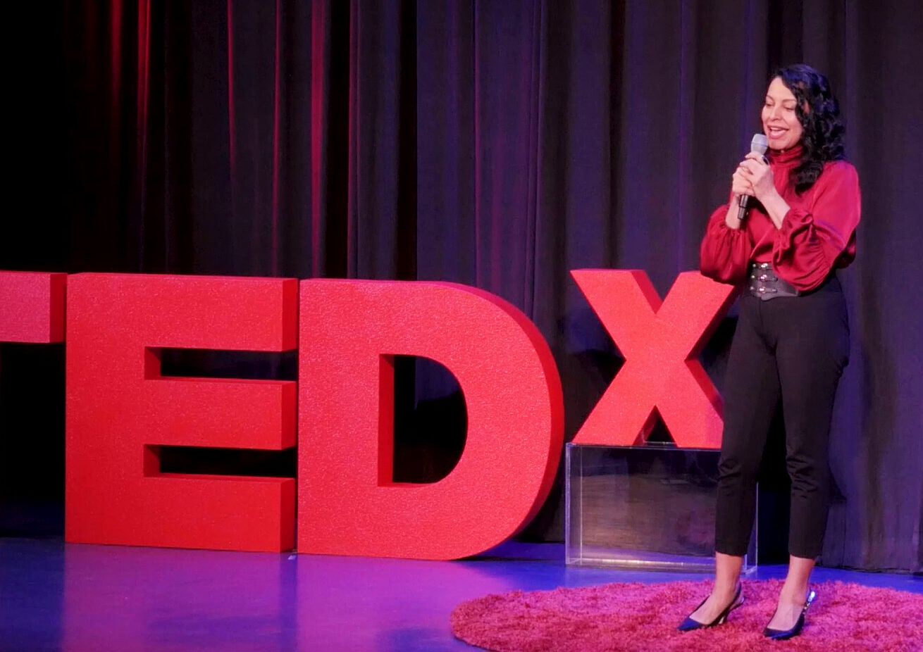 Emcee Mariza Brussolo hosting a TEDx event on stage