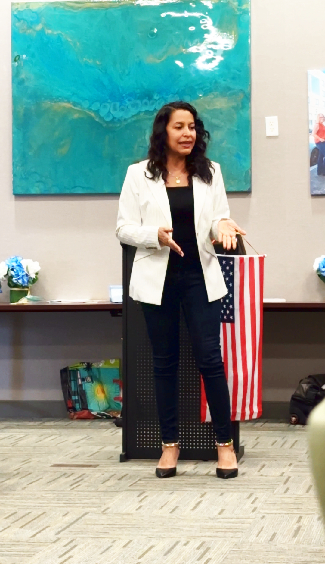 woman wearing a white blazer speaking at a meeting